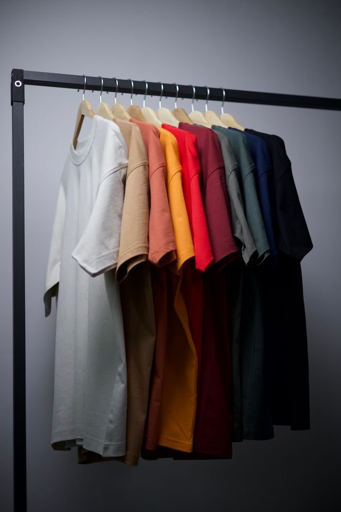 A range of colorful T-shirts neatly hung on a black clothing rack in an indoor setting.